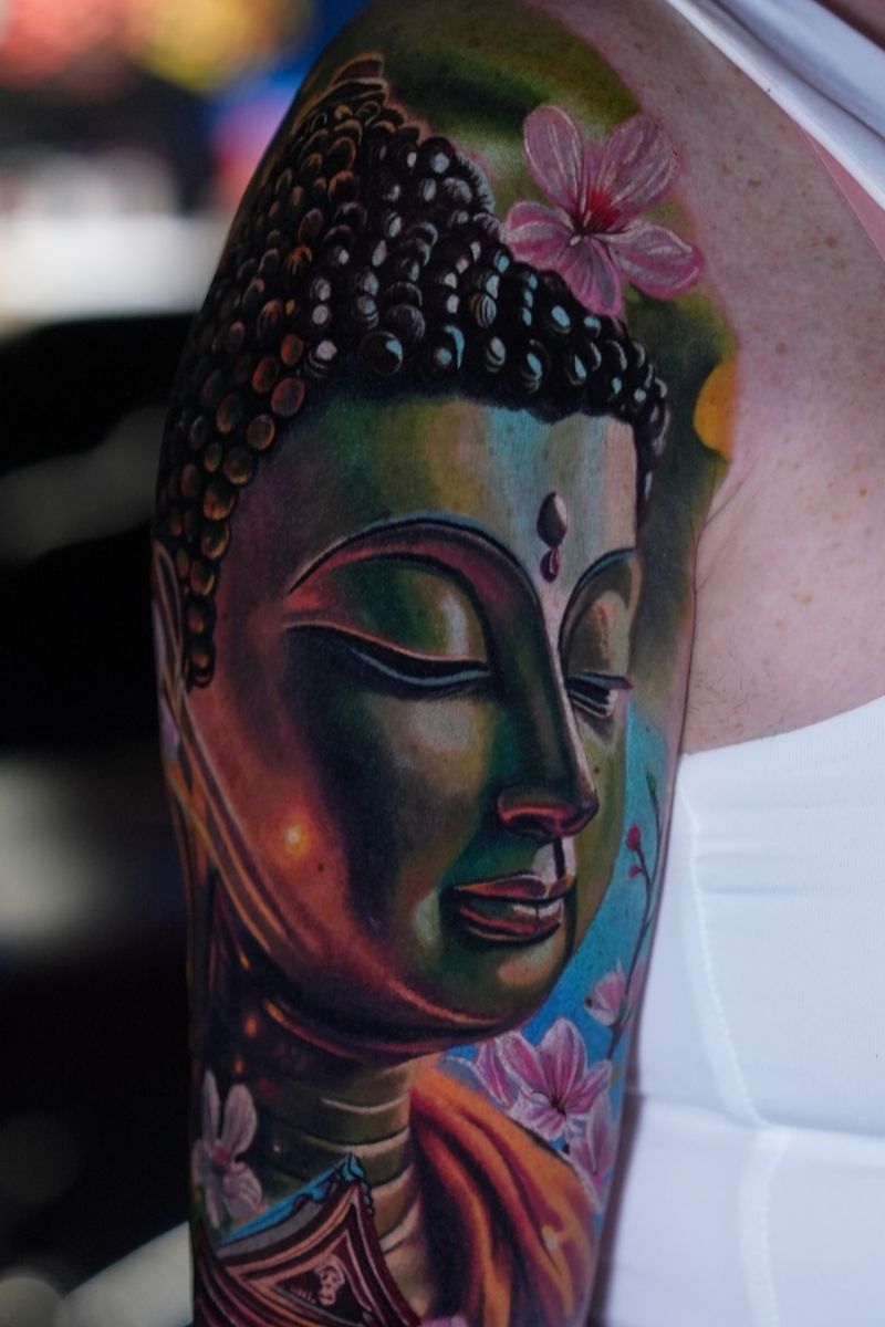 Color Buddha tattoo with multicolored shading and pink flowers